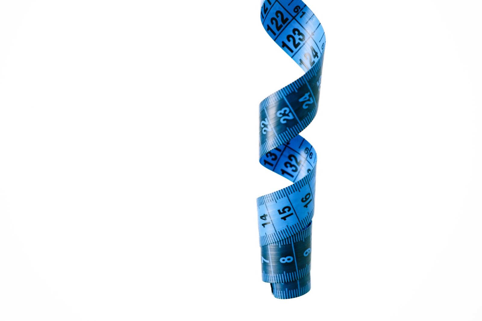 Blaues Maßband in Spiralen auf weißem Hintergrund, als Symbol für Präzision und Messung.